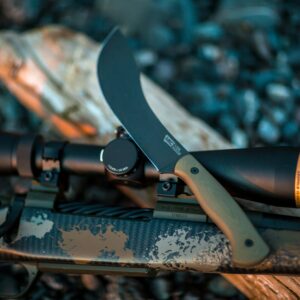 Detailed shot of a hunting knife resting on a camouflage rifle outdoors.