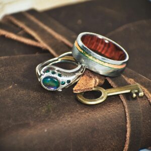 Close-up of exquisite rings on a leather journal with a vintage key, capturing elegance and craftsmanship.