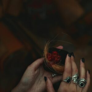 Detailed hands holding a small decorative item with intricate rings attached, showcasing creativity.
