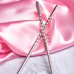 Two elegant stainless steel straws on soft pink silk fabric.