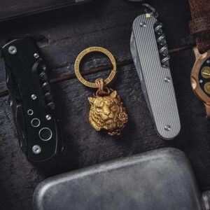 Close-up of lifestyle accessories including Swiss army knife, watch, and tiger key ring on a dark surface.