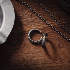 Artistic display of dragon scale cuff rings with an ashtray and chain on a wooden desk.