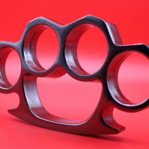 Detailed view of a metal brass knuckles on a vibrant red background.