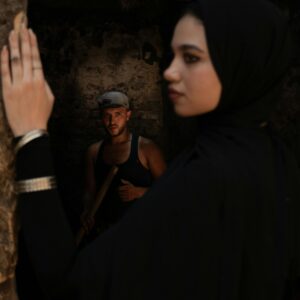 A captivating scene with a woman in a veil and a man in dark attire amidst a dark, mysterious backdrop.