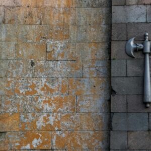 Worn stone wall with a decorative double-headed axe mounted on it.