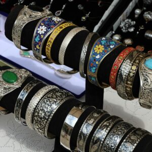 Colorful and intricate silver bracelets on display at a jewelry market stall, showcasing craftsmanship.