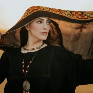 Portrait of a woman in a black dress with an ornate scarf, exuding elegance and cultural richness.