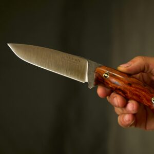 Detailed shot of a custom knife with a wooden handle ideal for outdoor use.