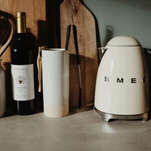 A modern kitchen setup featuring a Smeg kettle, wine bottle, and utensils for a stylish cooking space.
