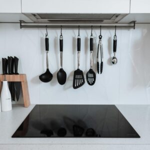Interior of spacious kitchen with light furniture and kitchenware placed in modern apartment in daytime