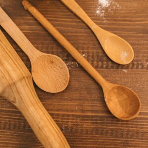 A collection of wooden kitchen utensils on a rustic wooden table, showcasing spoons and a rolling pin.